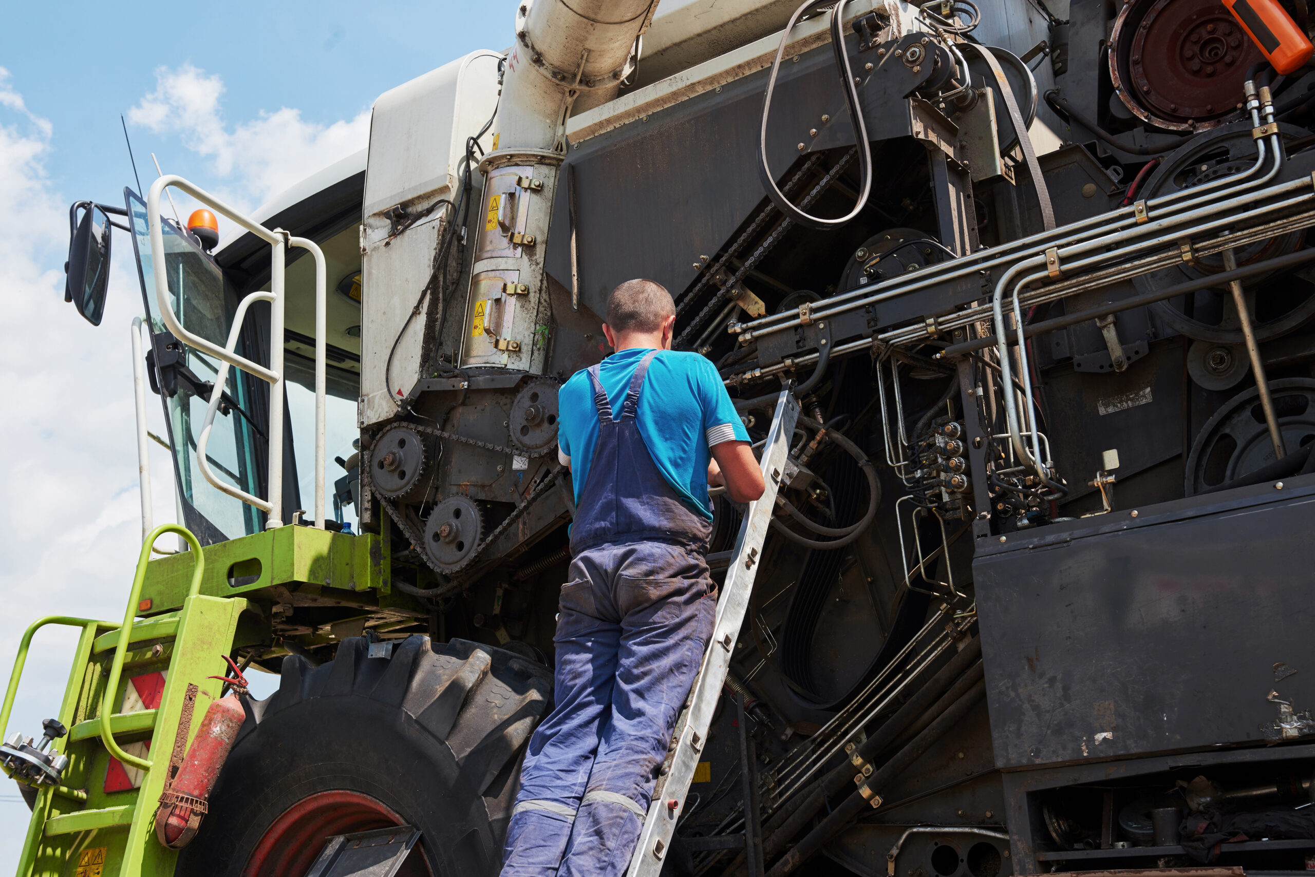 Combine machine service, mechanic repairing motor outdoors